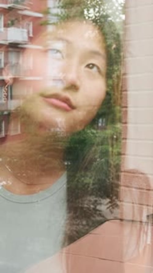 Outside view through glass of a girl looking out the window