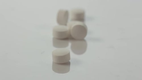 White pharmaceutical products, tablets, pills falling down against white background.
