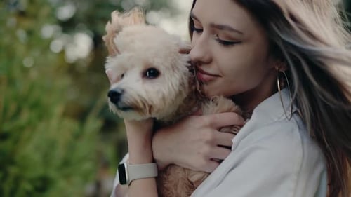 Woman Embraces Her Fluffy Small Dog in the Park Showing Love and Care
