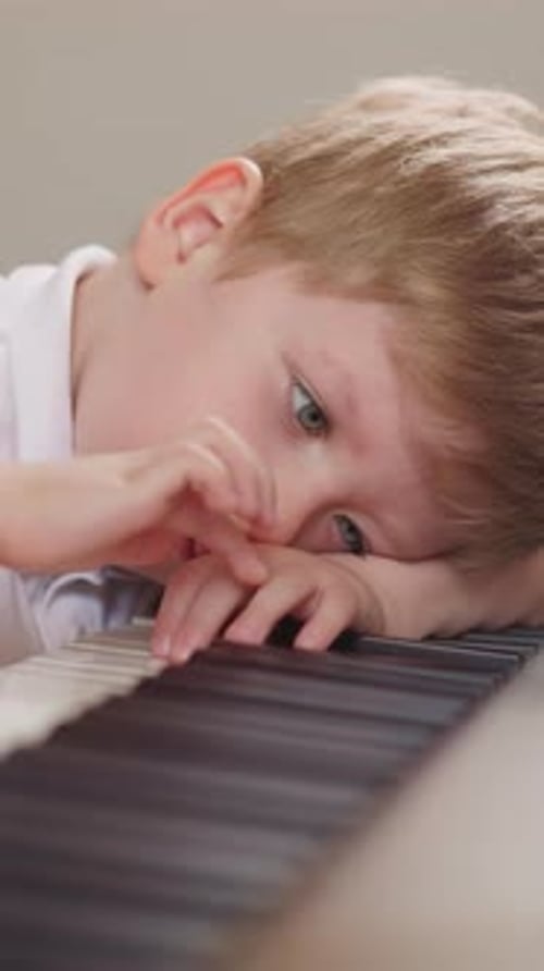 Fatigued Boy Lies and Presses Random Keys on Electric Piano