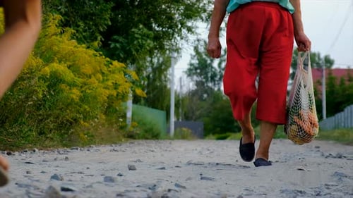 Adult and Child Walk with Produce on Rural Road