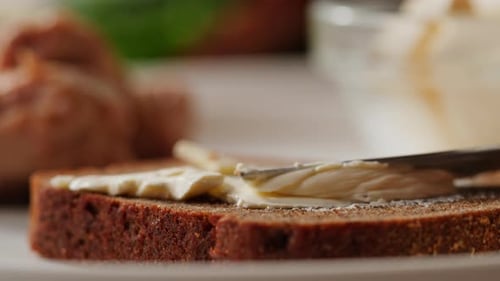 Cream Cheese Being Spread on Dark Bread