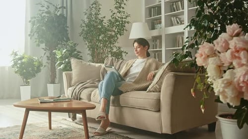 Woman Relaxes on Couch Using Tablet at Home