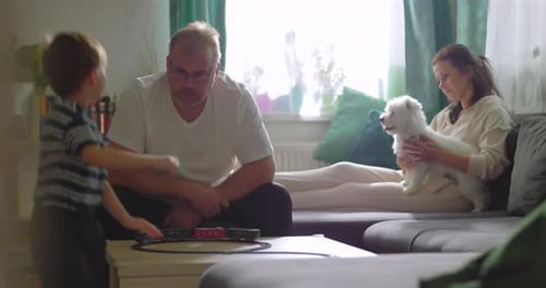 Family playing with train set and dog at home