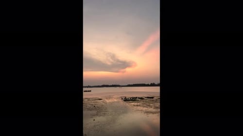 The golden sun dips below the horizon, casting a warm glow over the serene sunset lake.