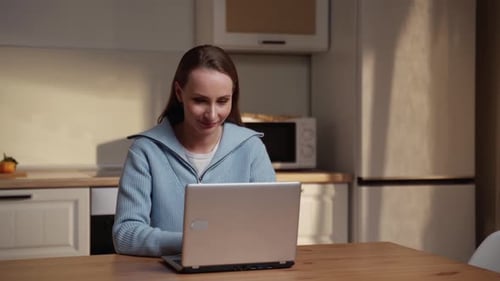 Woman Opens Laptop and Types in Bright Kitchen