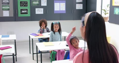 In school, students raising hands in classroom, engaging with teacher