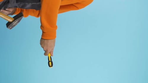 Vertical Video of Repairman in Industrial Work Clothes Handing Off Yellow Screwdriver Copy Space