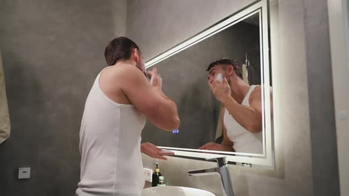 Homem raspando o rosto com navalha no banheiro moderno