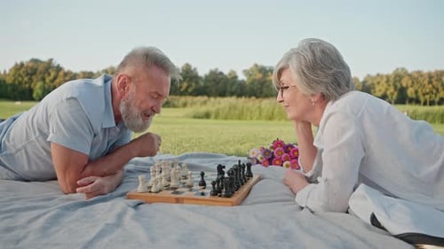 Senior Couple Playing Chess on Blanket in Park