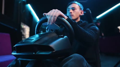 Auf dem Sitz. Der junge Mann spielt ein Rennspiel mit dem Fahrsimulator.