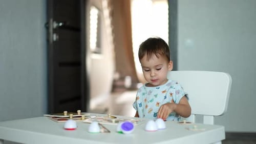Adorable cute toddler playing with toys at home. Lovely child collecting puzzles at the desk.