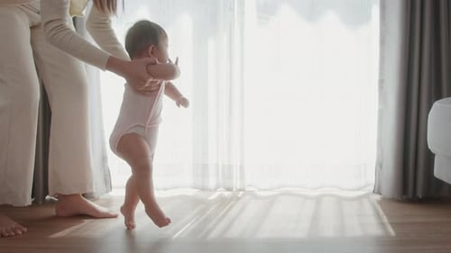 A baby girl learning first steps walk with mother, family, child, childhood and parenthood concept