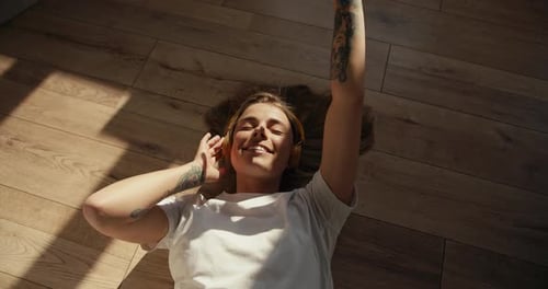 Tattooed Woman Listening to Music Lying on Floor