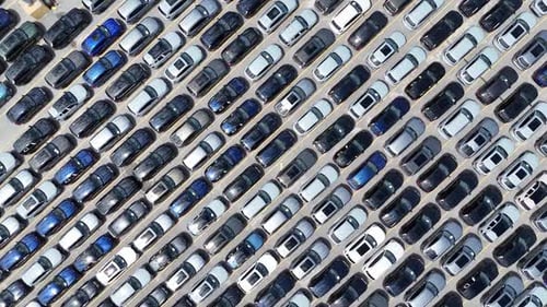 Aerial Overhead View of a Large Parking Lot Filled with Rows of New Cars Ready for Distribution