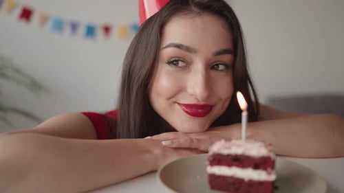 Young Woman Smiling at Birthday Cake with Candle