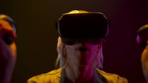 Woman Using VR Headset and Controllers in Dark Room