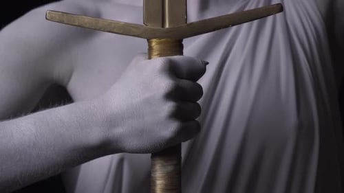 Close Up of a Hand of Themis with a Golden Sword and Face with Blindfold