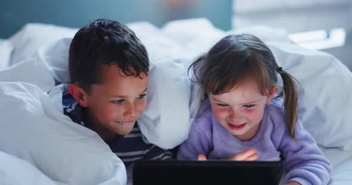 Brother and Sister Using Tablet in Bed