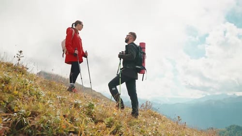 Couple Hiking Up a Mountain in Grassy Setting