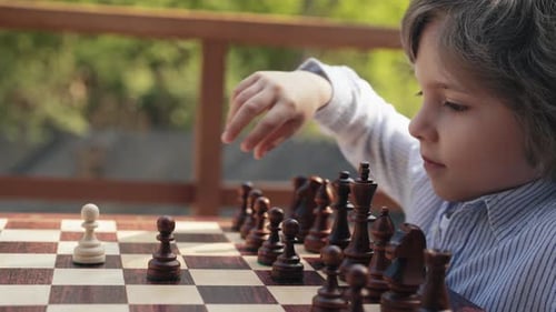 Chess Player Little Boy Strikes Pawn in Intense Move on Chessboard Sport Duel
