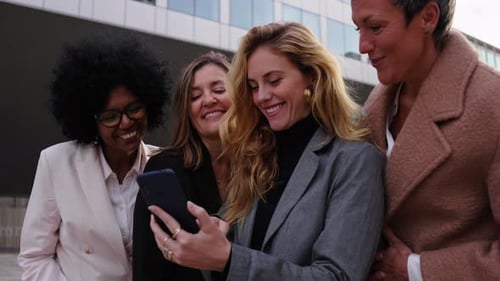 Smiling Women Look at a Smartphone