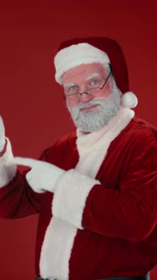 Vertical of Cheerful Santa Advertising Your Product against Red Background