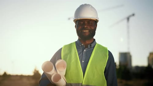 Smiling Construction Foreman in Safety Gear Holds Blueprints