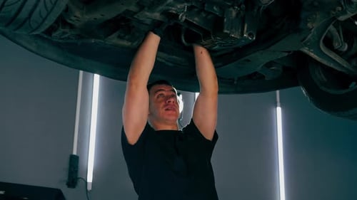 un mécanicien automobile d'une station-service vérifie qu'une voiture est soulevée sur un ascenseur et résout les problèmes liés à un