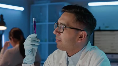 Close-up of Scientist Attentively Inspecting Test Tube Filled with Purple Liquid