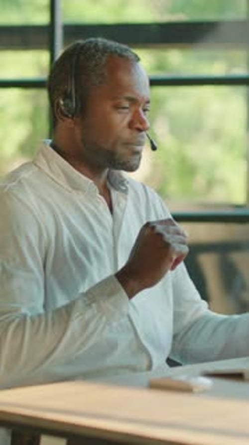 A Professional Man with a Headset is Diligently Working at His Desk in a Modern Office