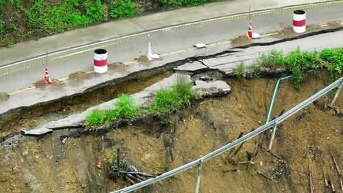 Landslide damage and fractured road surface seen from above.