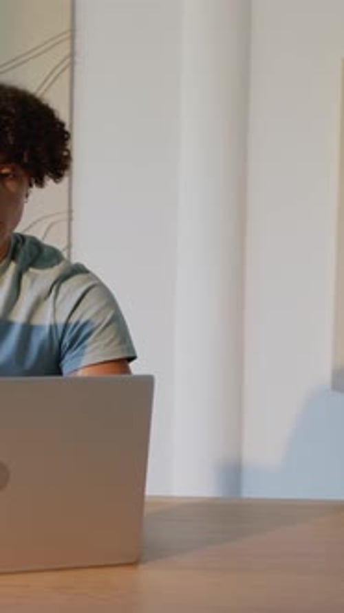 Vertical video: Students pointing at laptop screen while writing in notebook, typing in home office