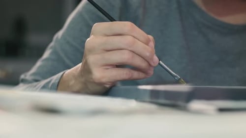 Close up of a female artist hand painting with a brush