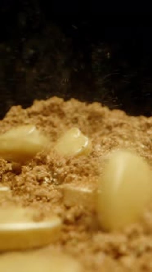Vertical video. Slow-motion: heart-shaped candies fall into golden powdered sugar.