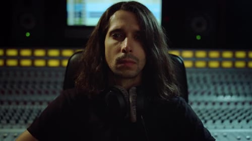 Young musician focused on music at recording studio looking to camera