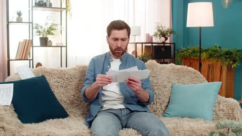 Frustrated Man Tearing Up Bills on Couch