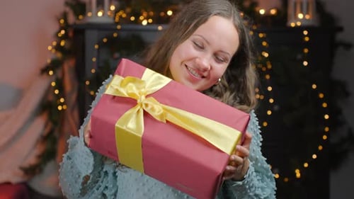 Woman Smiles and Holds a Christmas Gift