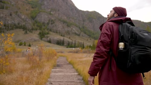Man walks away on field road in national park on adventure trip in picturesque landscape