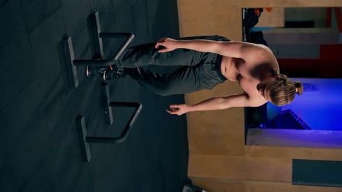 Vidéo verticale dans un club de sport, un entraîneur en pantalon de survêtement noir fait un exercice sur le sol