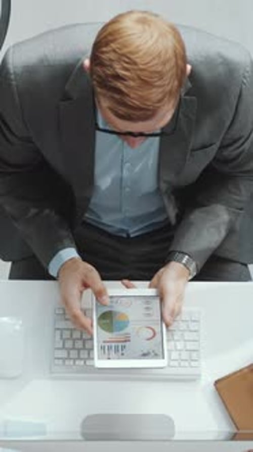 Male Office Worker Zooming in Diagrams on Digital Tablet at Workplace