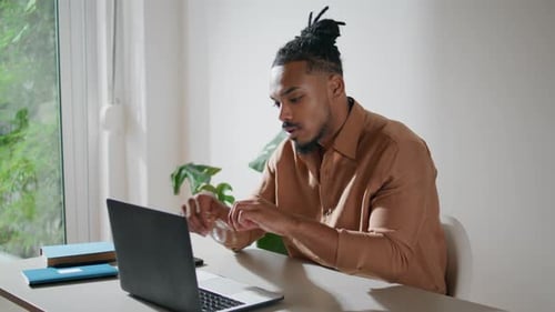 Focused Man Taking Glasses on in Office Closeup. Dreadlocks Guy Working Laptop