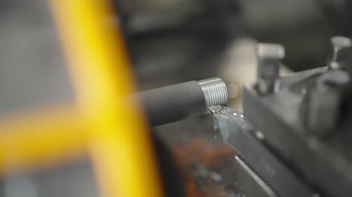 Closeup of a Metal Rod Being Threaded in a Lathe Machine