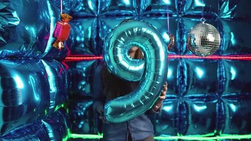 Woman Holds Number Nine Balloon in Blue Party Setting
