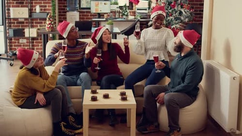 Funcionários do escritório tilintando copos com álcool na festa de Natal