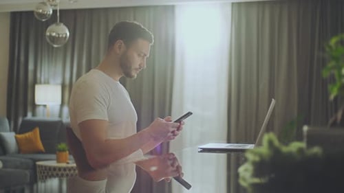 Young Adult Using Phone and Laptop at Home