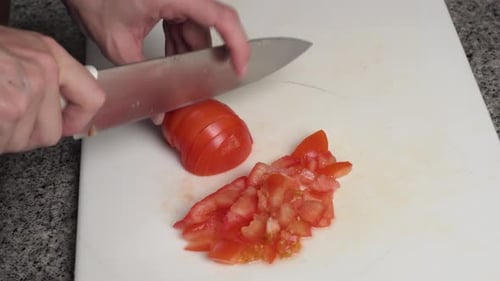 Man Chopping Fresh Tomato Into Pieces On The Board. - close up