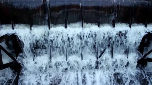 Wasser fließt aus einem großen Damm. Überlaufdamm. Wasser im Damm ablassen. Großer Wasserstrom