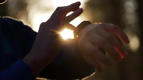 Man Touches Smartwatch in Golden Evening Sunlight