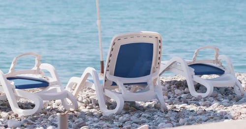 Rent of plastic sun loungers by sea, beach tourist season Sun protection, shade